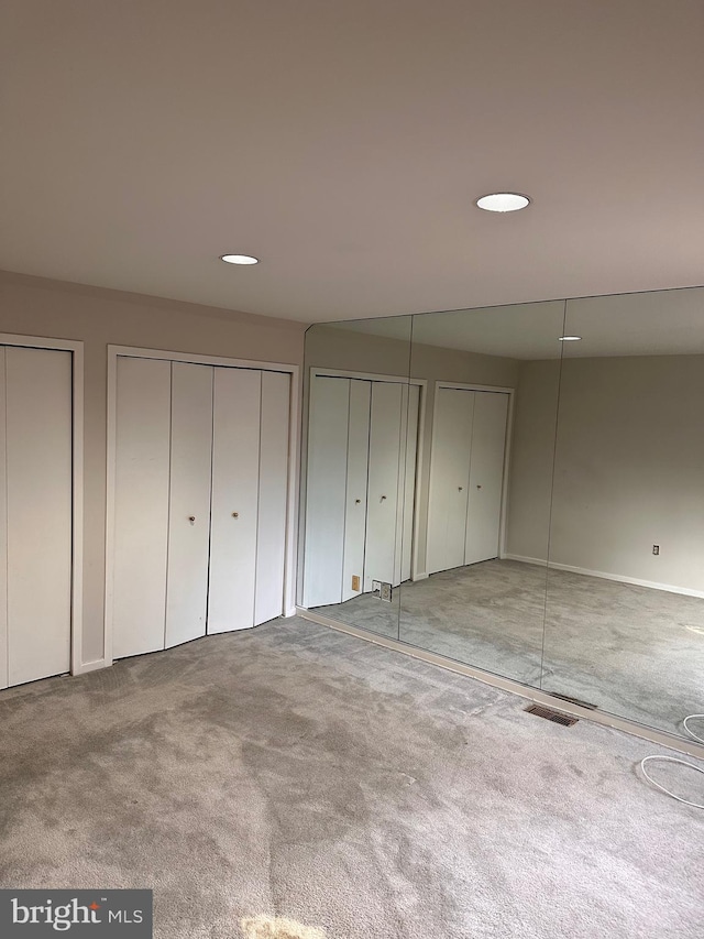 unfurnished bedroom featuring multiple closets and carpet flooring