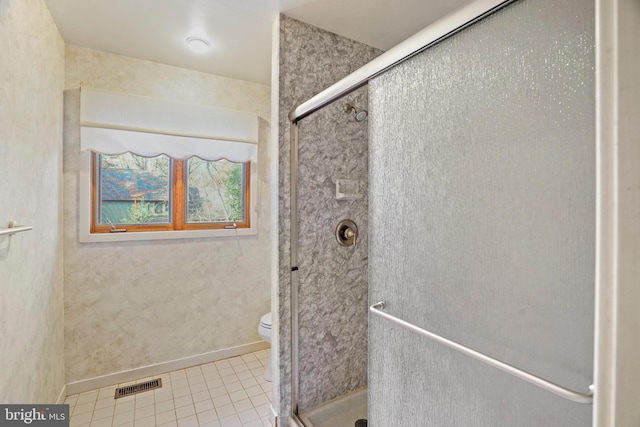 bathroom featuring tile patterned flooring, a shower with shower door, and toilet