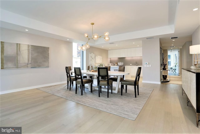 dining area with light hardwood / wood-style floors, an inviting chandelier, and a wealth of natural light