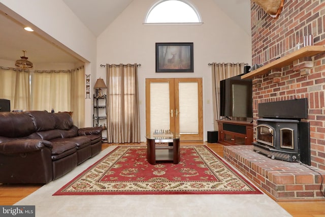 living room with a wood stove, french doors, high vaulted ceiling, and wood-type flooring