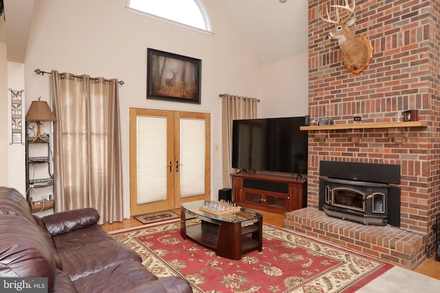 living room featuring wood-type flooring, a towering ceiling, a wood stove, and french doors