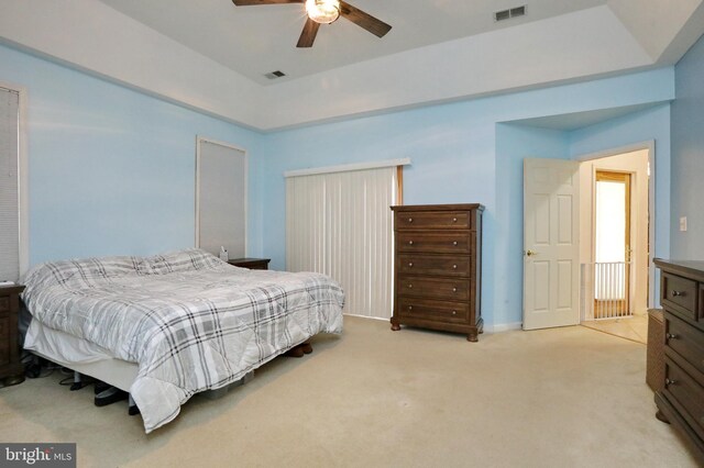 carpeted bedroom with ceiling fan and a tray ceiling