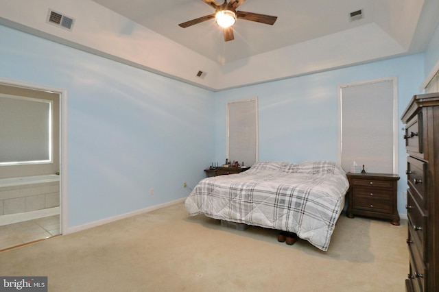 carpeted bedroom featuring a raised ceiling, ceiling fan, and ensuite bathroom