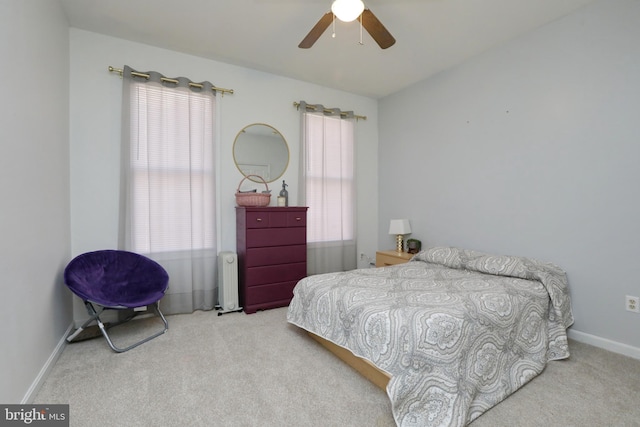 bedroom featuring ceiling fan, light colored carpet, radiator, and multiple windows