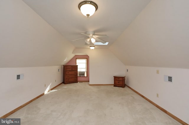 bonus room with vaulted ceiling with skylight, ceiling fan, cooling unit, and light colored carpet