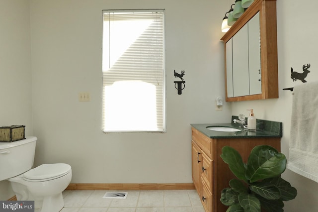 bathroom with tile patterned floors, vanity, a healthy amount of sunlight, and toilet