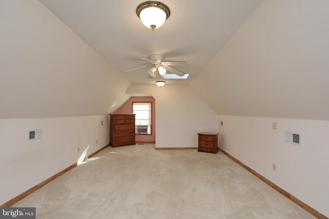 additional living space with ceiling fan, cooling unit, light colored carpet, and lofted ceiling with skylight