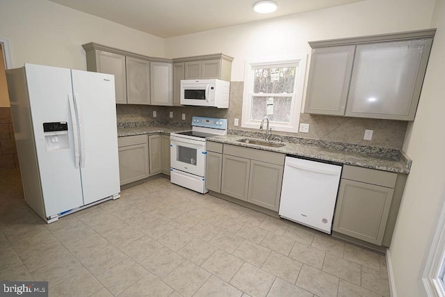 kitchen with gray cabinetry, light stone countertops, sink, tasteful backsplash, and white appliances