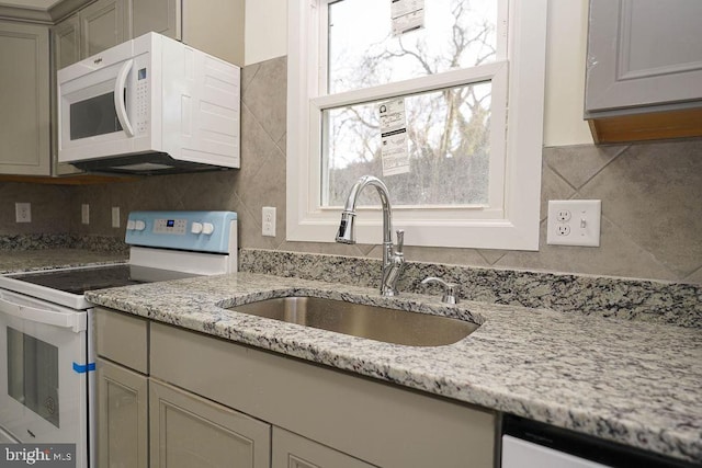 kitchen featuring gray cabinetry, light stone countertops, white appliances, and sink