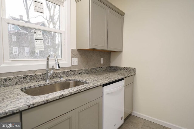 kitchen with a wealth of natural light, dishwasher, light tile patterned flooring, and sink