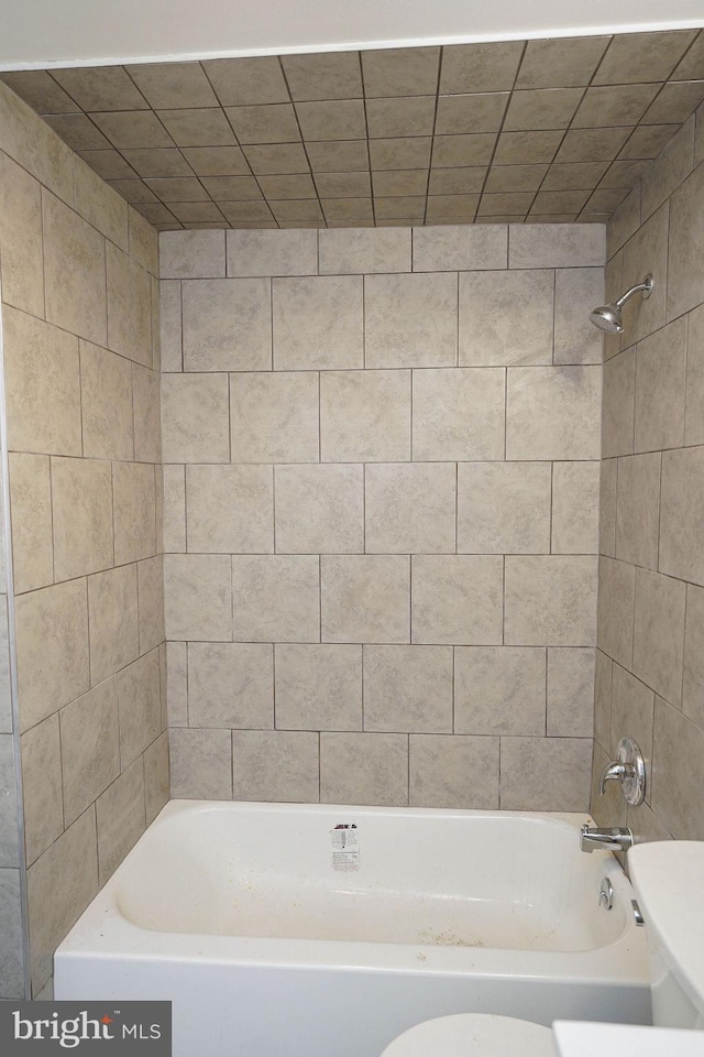 bathroom with toilet and tiled shower / bath