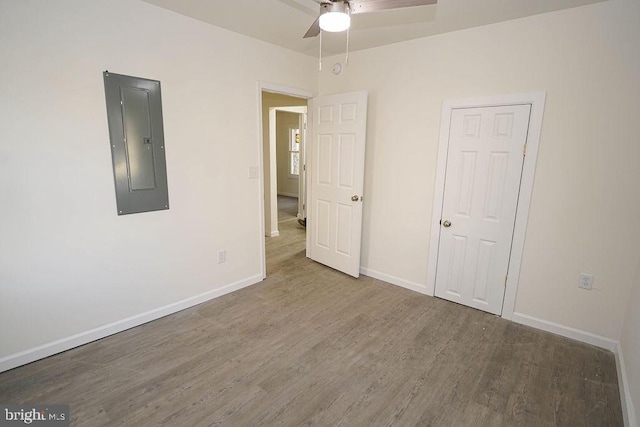 unfurnished bedroom with hardwood / wood-style floors, ceiling fan, and electric panel