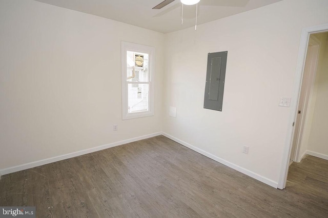 empty room featuring dark hardwood / wood-style flooring, electric panel, and ceiling fan