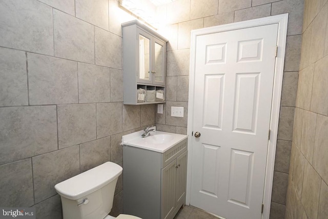 bathroom with vanity, toilet, and tile walls