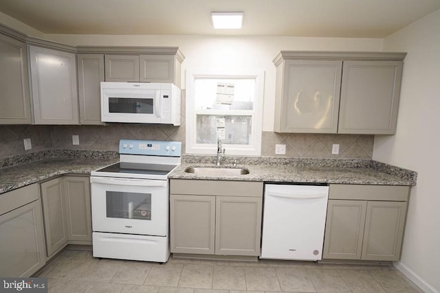 kitchen featuring sink, dark stone counters, white appliances, gray cabinets, and light tile patterned floors