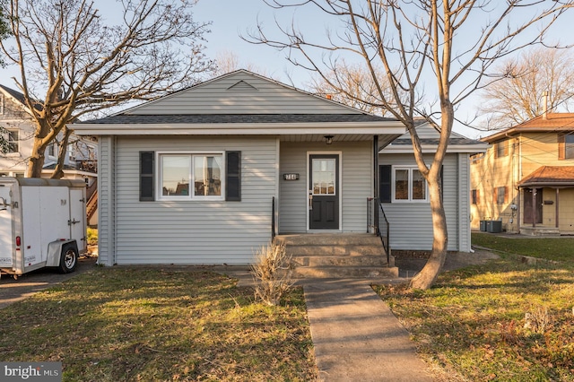 bungalow with central AC unit and a front yard