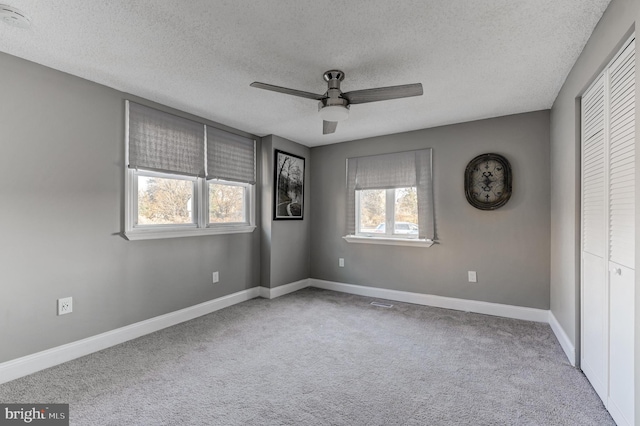 unfurnished bedroom with a closet, a textured ceiling, ceiling fan, and light colored carpet