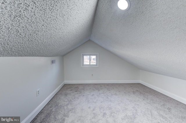 bonus room with lofted ceiling, carpet floors, and a textured ceiling