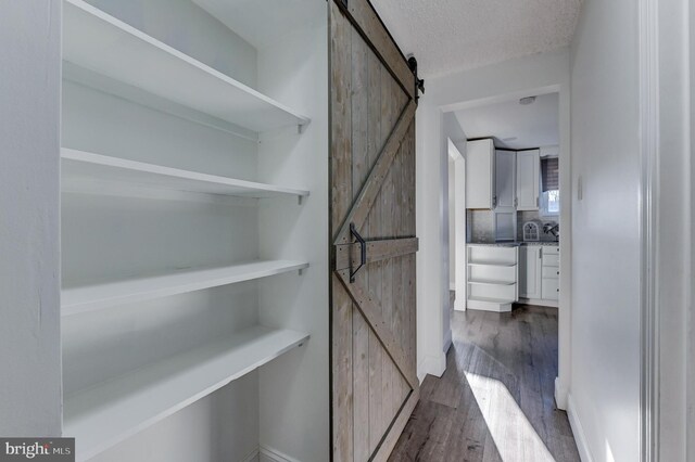 hallway with dark hardwood / wood-style flooring, a barn door, and a textured ceiling