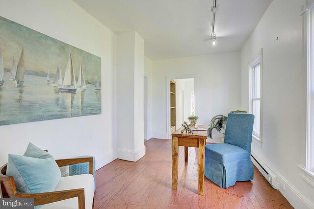 living area featuring wood-type flooring and a baseboard heating unit