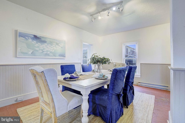 dining room featuring wood-type flooring, rail lighting, and a baseboard heating unit