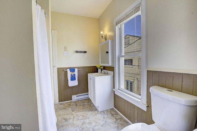 bathroom with vanity, toilet, wooden walls, and a baseboard radiator