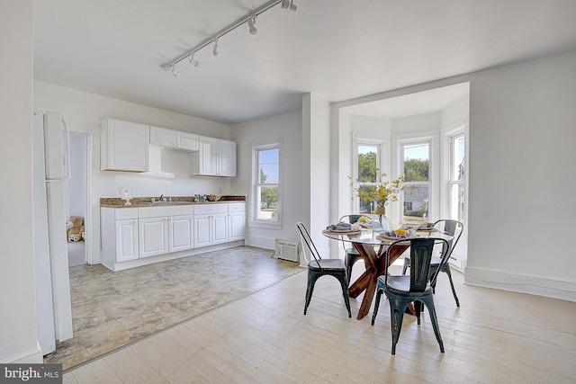 dining space featuring sink, track lighting, and light hardwood / wood-style flooring