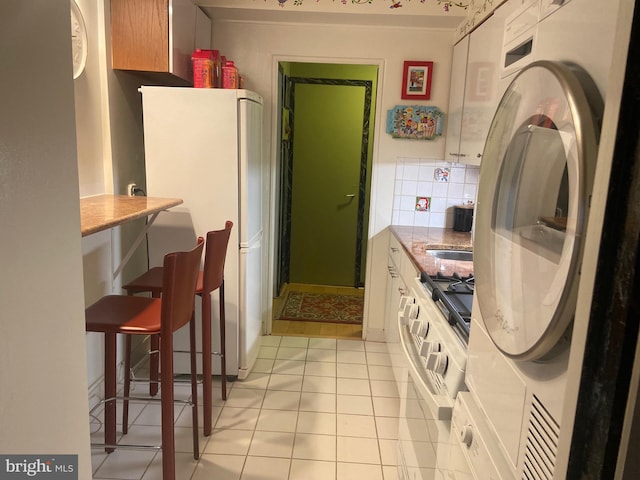 kitchen featuring light tile patterned flooring, white refrigerator, decorative backsplash, and refrigerator