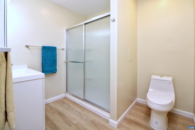 bathroom with wood-type flooring, vanity, toilet, and walk in shower