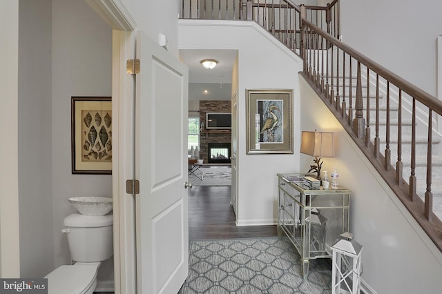 interior space with wood finished floors, stairway, baseboards, and a towering ceiling