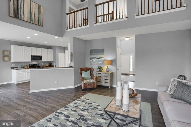 living area with recessed lighting, baseboards, dark wood finished floors, and a towering ceiling