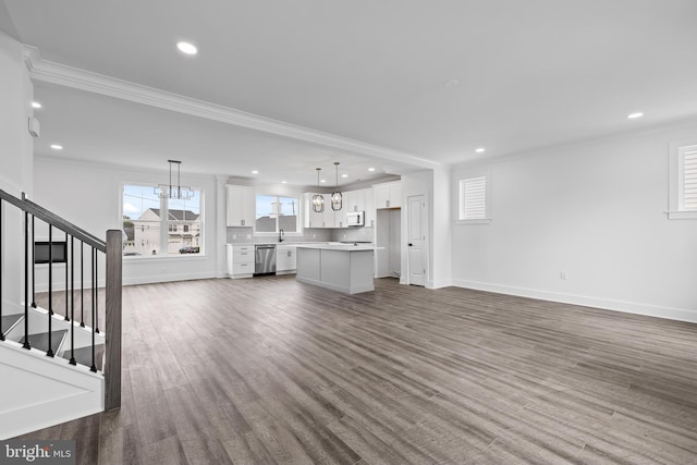 unfurnished living room featuring stairway, dark wood finished floors, recessed lighting, crown molding, and a notable chandelier