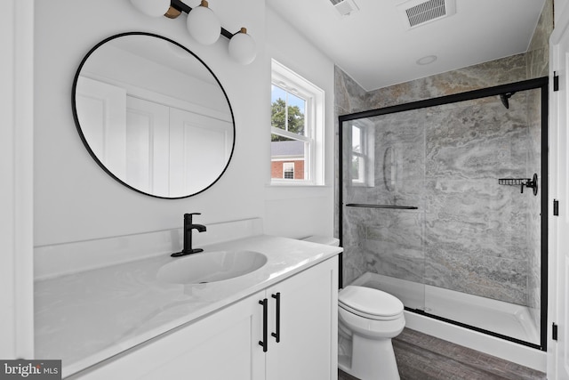 bathroom featuring vanity, a shower with shower door, and toilet