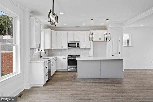 kitchen with ornamental molding, a sink, backsplash, stainless steel appliances, and light countertops