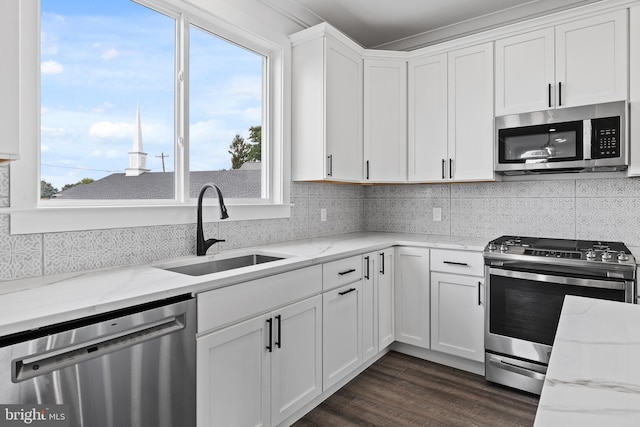 kitchen with a sink, stainless steel appliances, dark wood-type flooring, white cabinetry, and backsplash