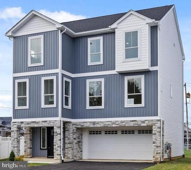 view of front of home featuring aphalt driveway, stone siding, and an attached garage