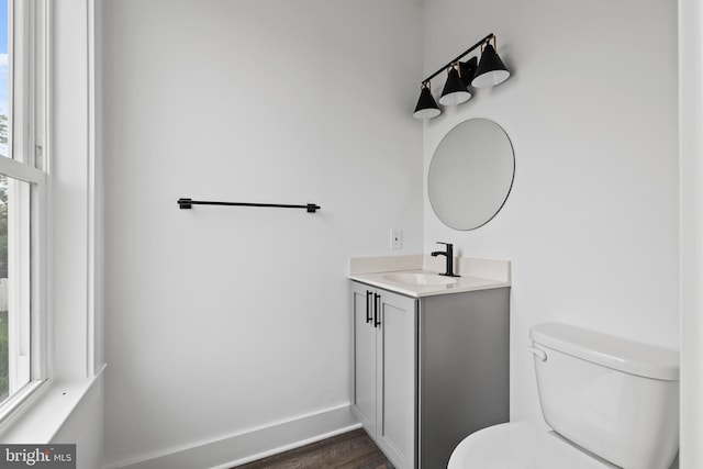 half bathroom with baseboards, toilet, wood finished floors, and vanity