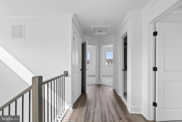 hall featuring visible vents, dark wood-type flooring, baseboards, ornamental molding, and an upstairs landing