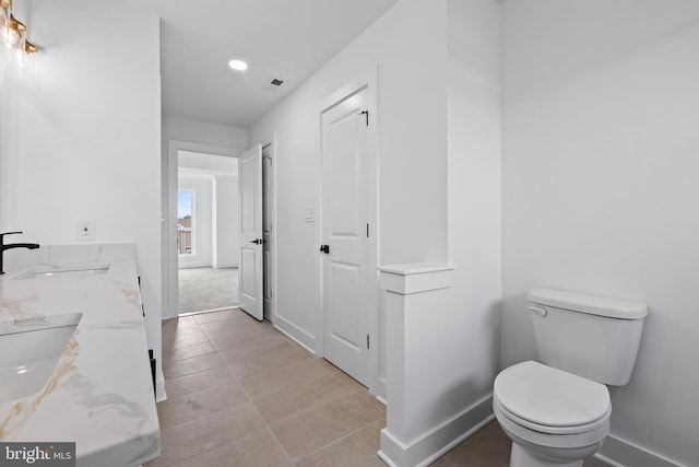 bathroom with toilet, baseboards, and a sink