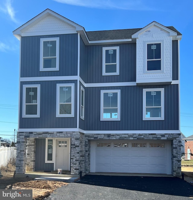 view of front of property with aphalt driveway, stone siding, and an attached garage