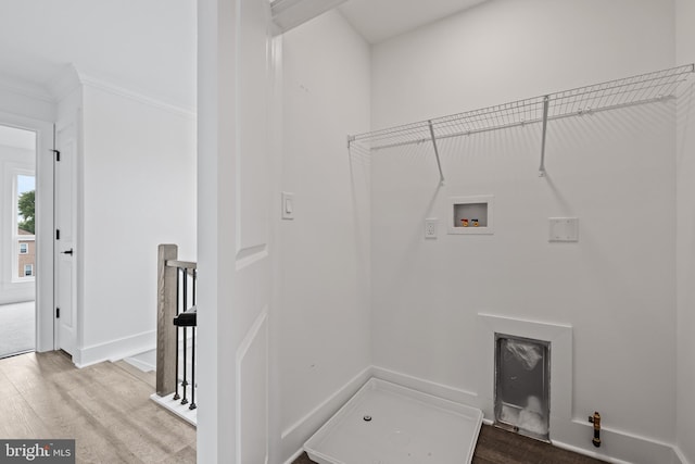 clothes washing area featuring hookup for a washing machine, wood finished floors, baseboards, and ornamental molding