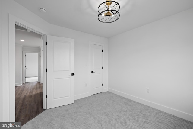 unfurnished bedroom with an inviting chandelier, carpet flooring, and baseboards