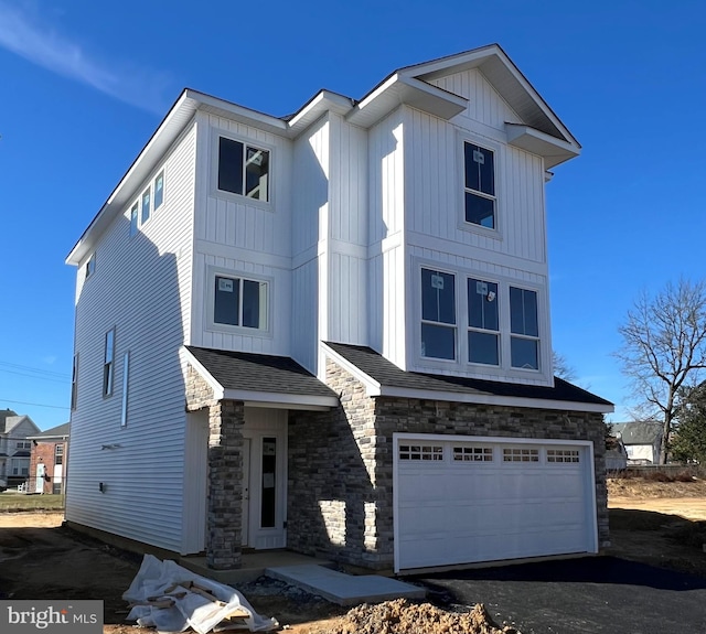 view of front facade featuring aphalt driveway, stone siding, board and batten siding, and a garage