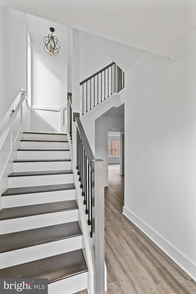 staircase featuring a high ceiling, wood finished floors, and baseboards