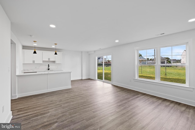 unfurnished living room with a sink, baseboards, dark wood-style floors, and recessed lighting