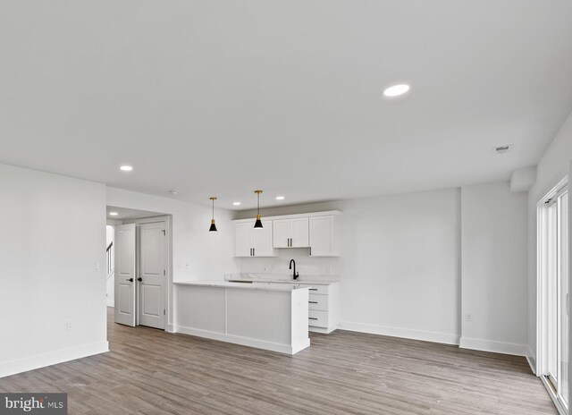 unfurnished living room with wood finished floors, visible vents, baseboards, recessed lighting, and a sink