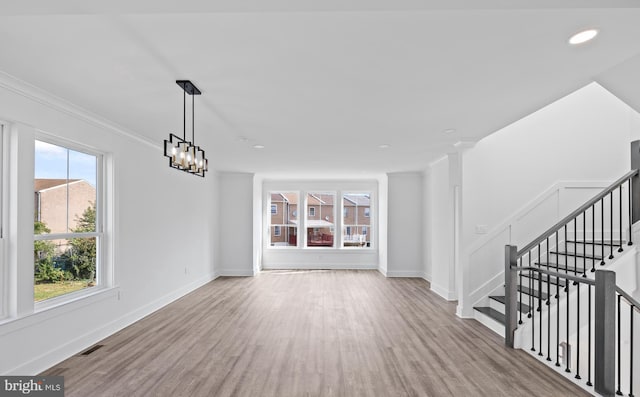 unfurnished living room featuring visible vents, baseboards, and wood finished floors