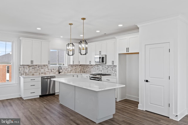 kitchen featuring ornamental molding, white cabinetry, stainless steel appliances, and a sink