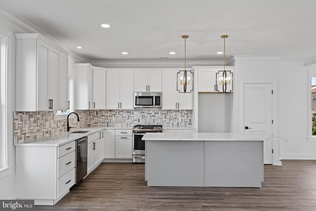 kitchen featuring ornamental molding, a sink, a kitchen island, white cabinetry, and appliances with stainless steel finishes