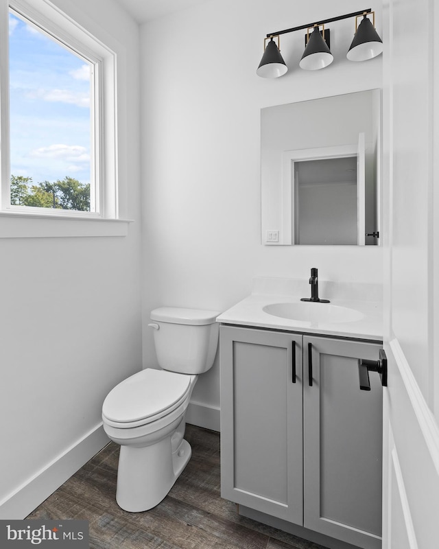 bathroom featuring toilet, vanity, baseboards, and wood finished floors